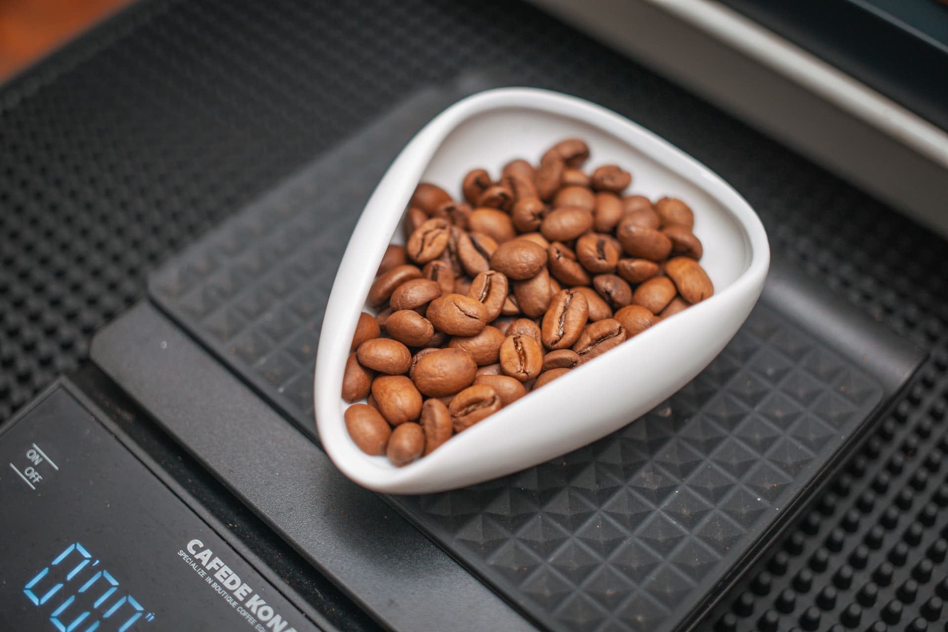 A digital coffee scale with beans on the platform