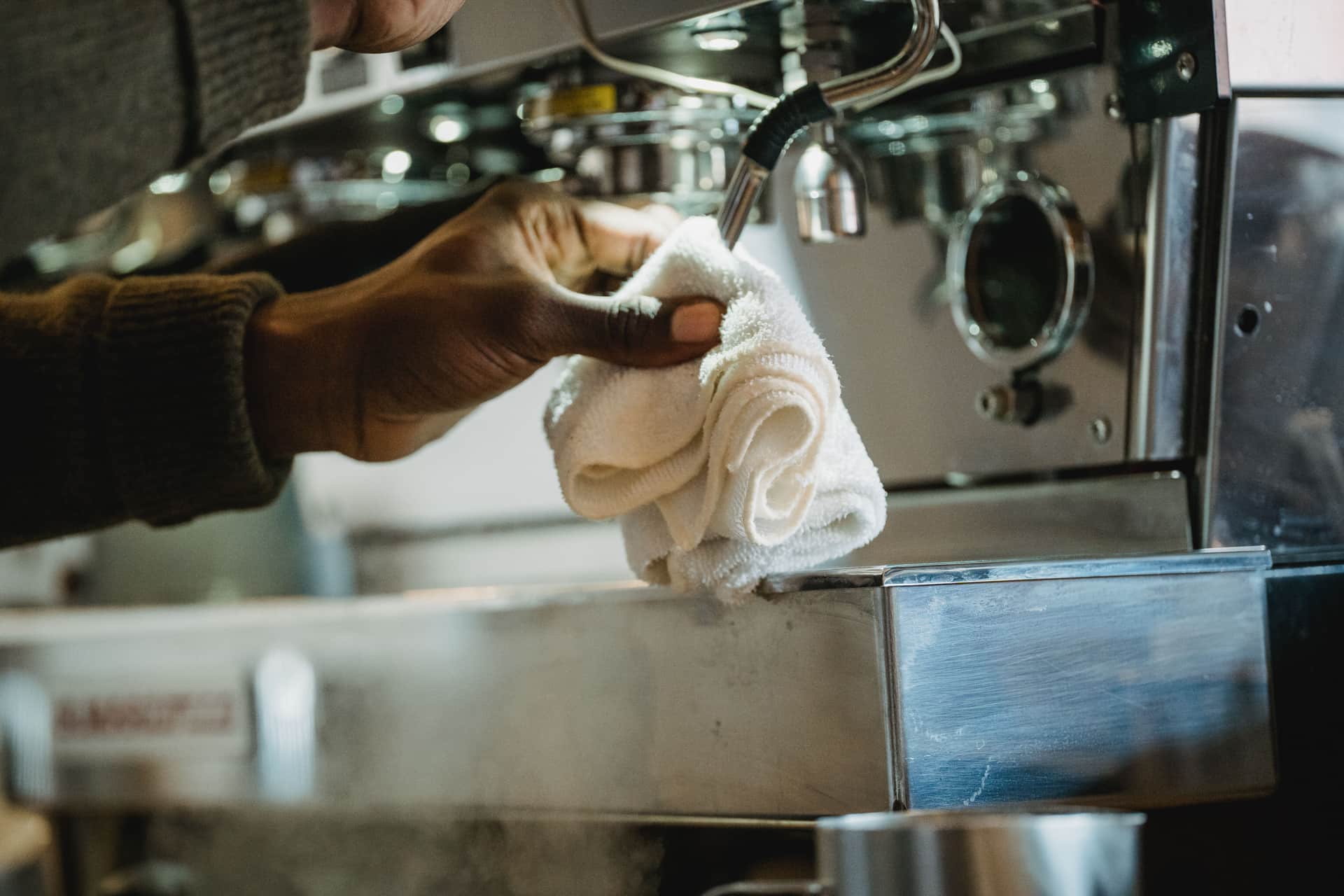 An espresso machine being cleaned with a cloth